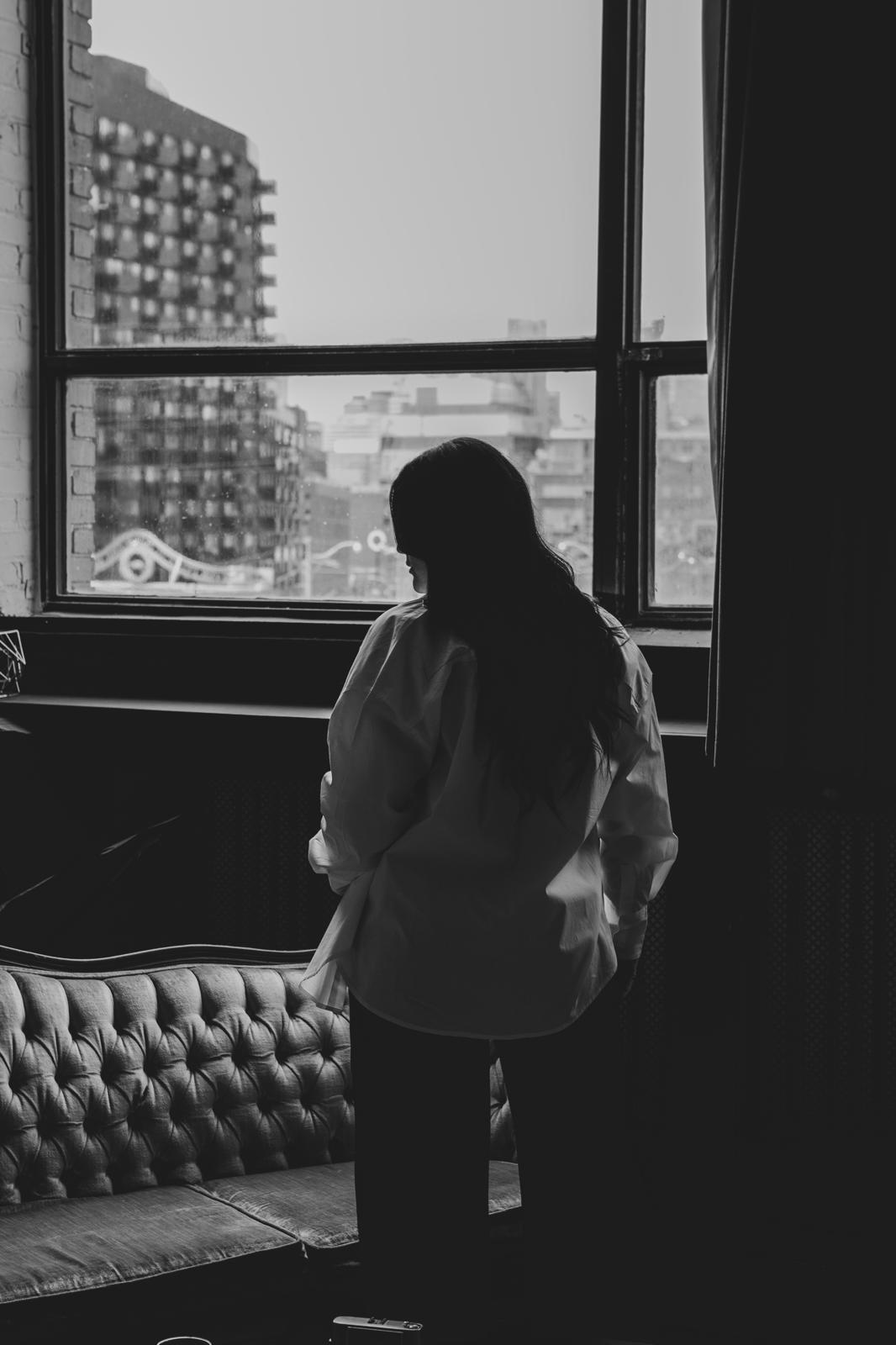 author standing beside a couch in front of a large window